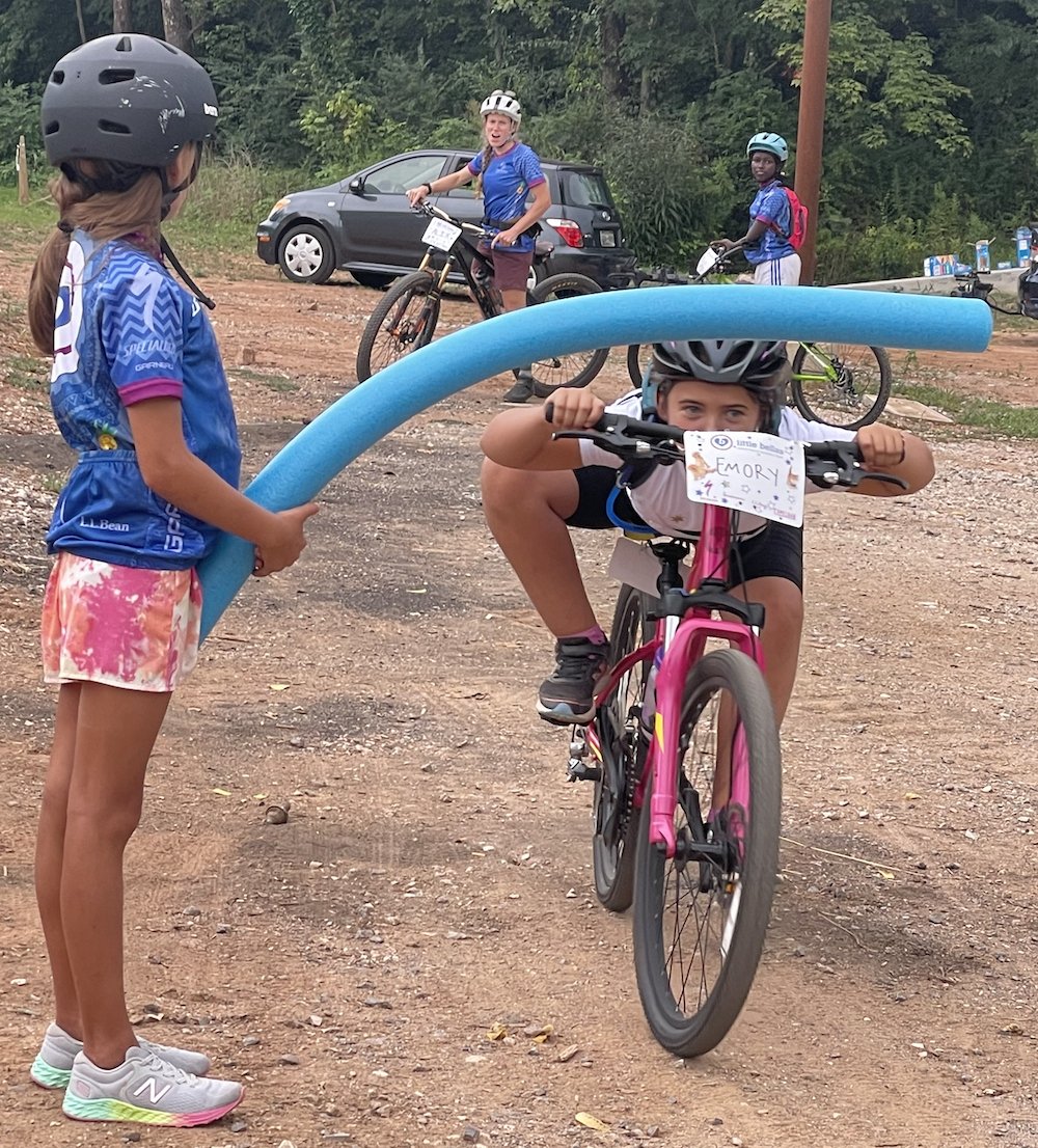 Girl limbo-ing under a pool noodle